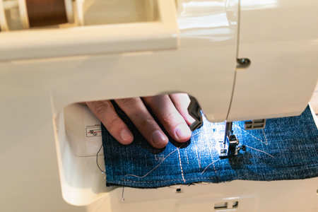 Man using a sewing machine with a blue garment, for repair work, customization, creation, upcycling