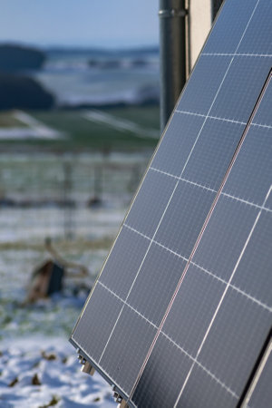 Solar panels with snow on ground on a well-exposed wall of an individual house, making savings...