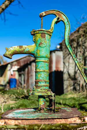Old hand water pump on a well in the garden, watering and saving water, rural environmentの写真素材