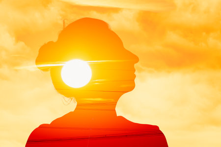 Woman in profile looking upwards on a sunrise background, double exposure energy, relaxation, wellbeingの写真素材