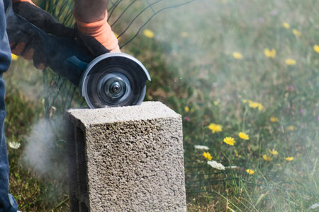 A bricklayer works on blocks to build a wall on a construction site with concrete, a trowel, a level and a grinderの写真素材
