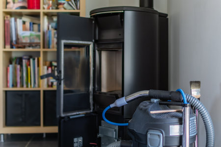 Cleaning a pellet stove with a vacuum cleaner and a brushの写真素材