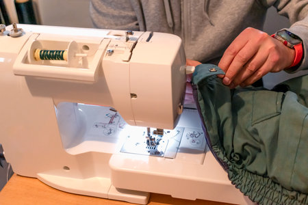 Man using a sewing machine with a garment, for repair work, customization, creation, upcycling