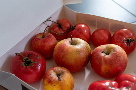 Green tomatoes in a cardboard box, the ethylene released by the apples helps the tomatoes ripenの写真素材