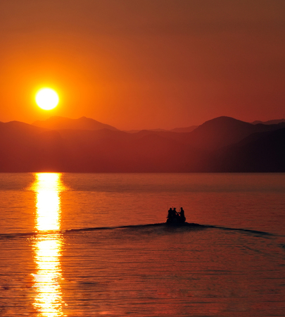 fishermen boat leaving harbour at sunsetの写真素材