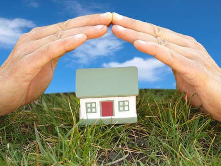 his hands are covered toy house which stands on the grassの写真素材