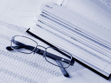 Daily book and glasses on financial figures. Toned blue. Shallow DOF.の写真素材