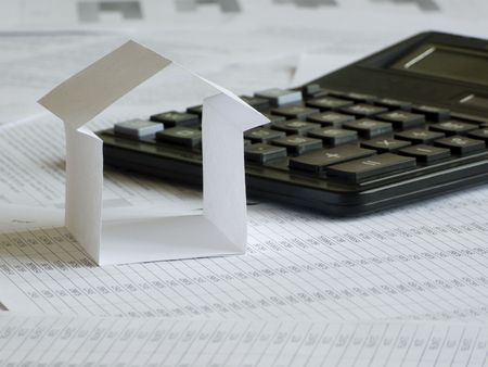 Paper house and calculator on financial documents. Shallow DOF.の写真素材