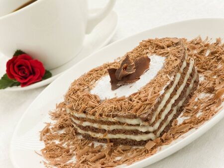 Plate with sweet chocolate heart-shaped cake and coffee cup. Shallow dof.の写真素材