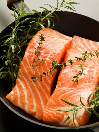 Frying pan with two salmon steaks and herbs, Shallow dof.の写真素材