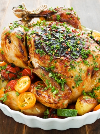 Whole roasted chicken with vegetables, herbs and fruitsの写真素材