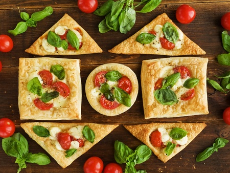Puff-pizzas with mozzarella cheese, cherry tomatoes and baby basil. Viewed from above.の写真素材