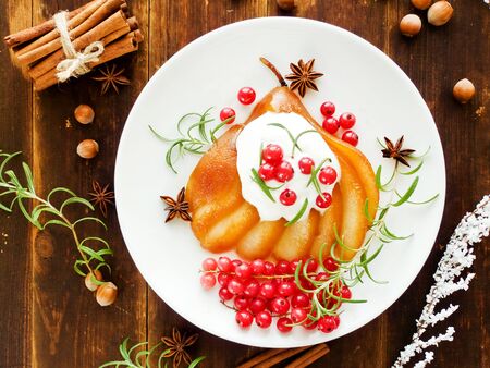 Christmas dessert poached pear with nuts, fruits and cream. Shallow dof.の写真素材