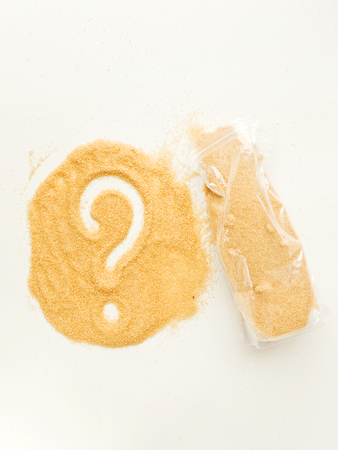 Brown sugar with question mark and plastick pack on white wooden background. Shallow dof.の写真素材