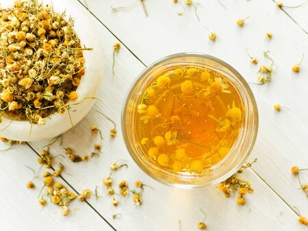 Dry camomile tea on wooden background. Shallow dof.の写真素材