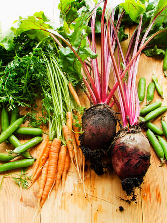 Beetroots, carrots and green peas wooden background. Shallow dof.