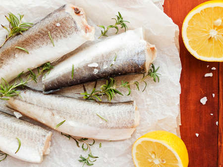 Fresh hake fish with salt, rosemary and lemon. Shallow dof.