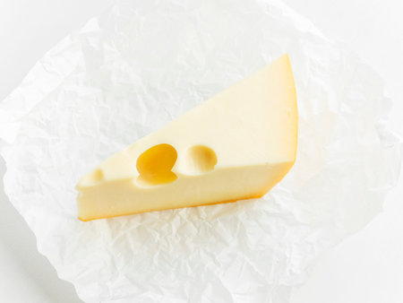 A piece of hard cheese on the white wooden background. Shallow dof.の写真素材