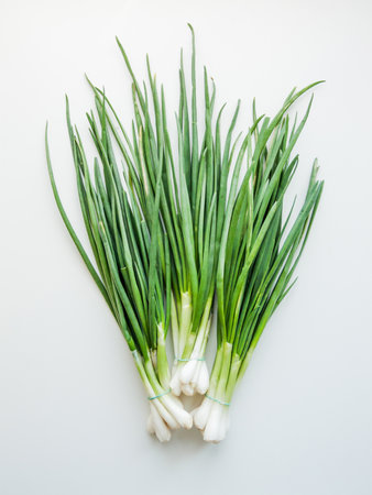 Seasonal diet and nutrition, healthy eating concept. Fresh green leek onion on the white wooden background, top view bunch of greens on the table.の写真素材