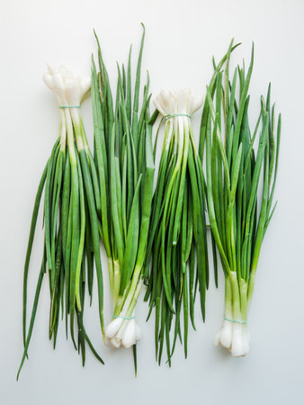 Seasonal diet and nutrition, healthy eating concept. Fresh green leek onion on the white wooden background, top view bunch of greens on the table.の写真素材