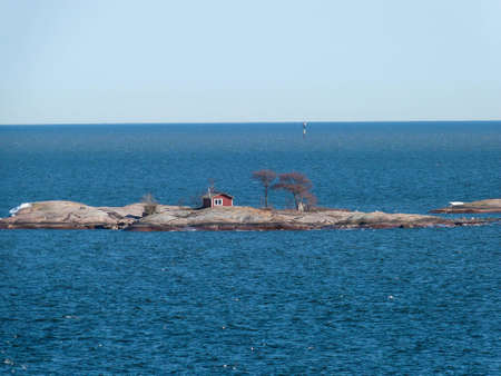little red swedish wooden house on rocks in baltic seaの写真素材