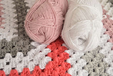 woolen balls with crochet granny square blanket in basket and crochet hook and scissors