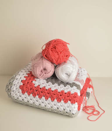 woolen balls with crochet granny square blanket in basket and crochet hook and scissors