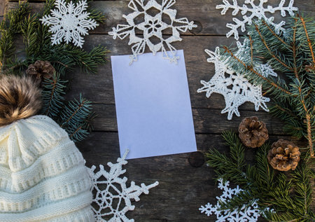 crochet snowflake ornaments on wooden ground with space for text and fir branch and cones and a knitted bobble hat backgroundの写真素材