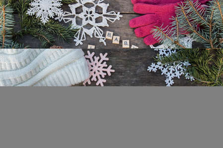 crochet snowflake ornaments on wooden ground with winter slogans and fir branch and cones and a...