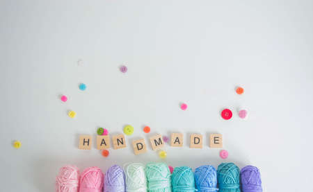 Colorful woolen yarn balls, buttons and with crochet hooks and wooden letters and space for text backgroundの写真素材