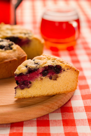 Piece of the pie with berries on wooden board, in the background  a cup of teaの写真素材