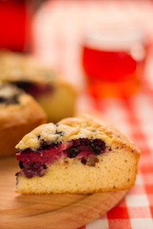Piece of the pie with berries on wooden board, in the background  a cup of teaの写真素材