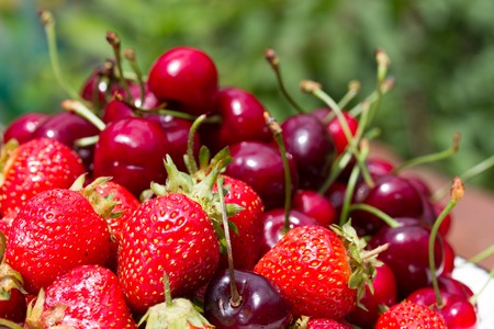 fresh sweet strawberry and cherry in the bowl on wooden backgroundの写真素材