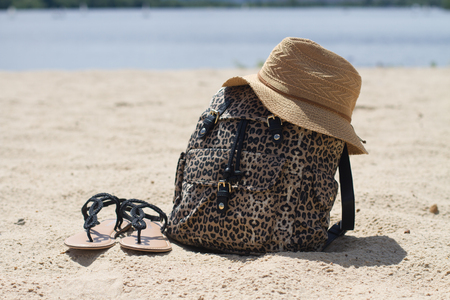 beautiful bag, straw hat, sandals on the golden sand, summer day, waterの写真素材