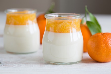 Home made panna cotta with mandarin jam on a wooden background. tangerines in the background, close-upの写真素材