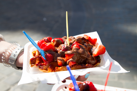 Tourists holding a delicious fresh brussels waffles with strawberries and chocolateの写真素材