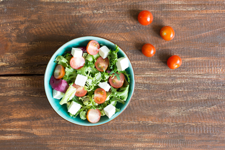 Salad with cherry tomatoes, Radicchio lettuce, frize, arugula and feta on wooden tableの写真素材