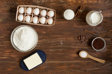Ingredients for making cinnamon rolls on a wooden background . Flour , sugar, egg , chocolate , cocoa , cinnamon and butter. Close up. Top viewの写真素材