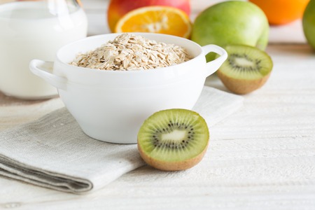 Tasty oatmeal with apples, kiwi, orange and milk on wooden table, Healthy breakfast, close upの写真素材