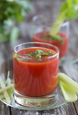 Tomato juice in a glass with celery and tomatoes on a wooden tableの写真素材