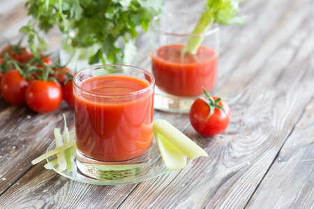 Tomato juice in a glass with celery and tomatoes on a wooden tableの写真素材