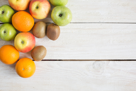 Ripe apples, orange and kiwi on a wooden table. top viewの写真素材
