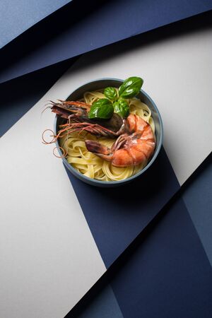 Pasta with shrimps, Penaeus monodon, and basil in a plate, close-up, top view.の写真素材