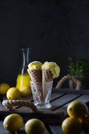 Delicious homemade ice cream in waffle cups. Lemon gelato. Limoncello in the backgroundの写真素材