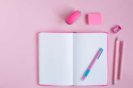 School notebook and stationery on a pink background.