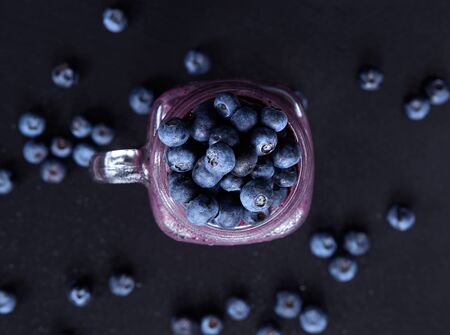 Berry smoothie on dark background with copy space. Summer drink cocktail. Healthy eating dieting and breakfast concept. Delicious blueberry smoothie in a glass jar mug. Vegetarian Top view.の写真素材