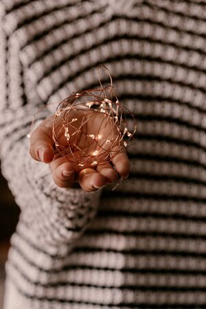 Copper string light in woman hands. Christmas mood and atmosphere. Blurred photos, bokeh.の写真素材