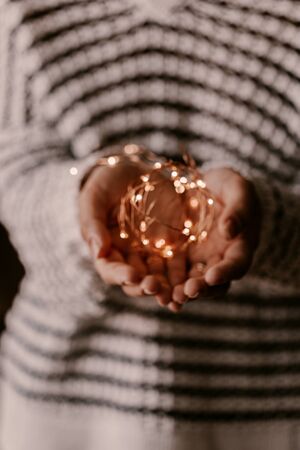 Copper string light in woman hands. Christmas mood and atmosphere. Blurred photos, bokeh.
