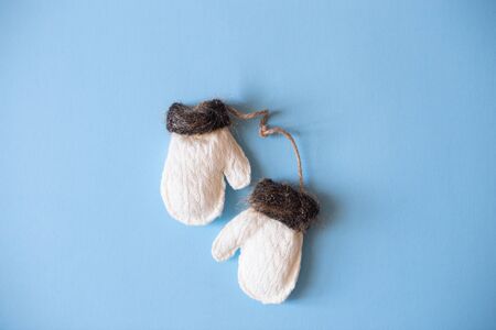 Christmas mood flat lay. Happy New Year flat lay on the paper. White woolen mittens with brown fur on blue paper.の写真素材