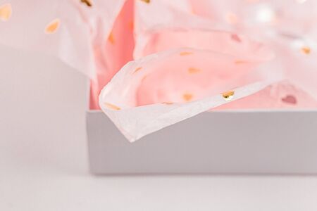 Pastel pink gift paper with golden hearts in white present box. Gift wrapping for special occasion....